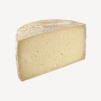 Un corte detallado del queso artesano manchego, revelando la textura suave y cremosa obtenida del envejecimiento en manteca.