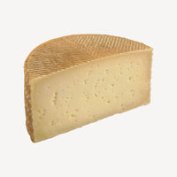 Una vista detallada del queso curado manchego, mostrando la consistencia y calidad que se desvela en cada capa de este clásico artesanal.