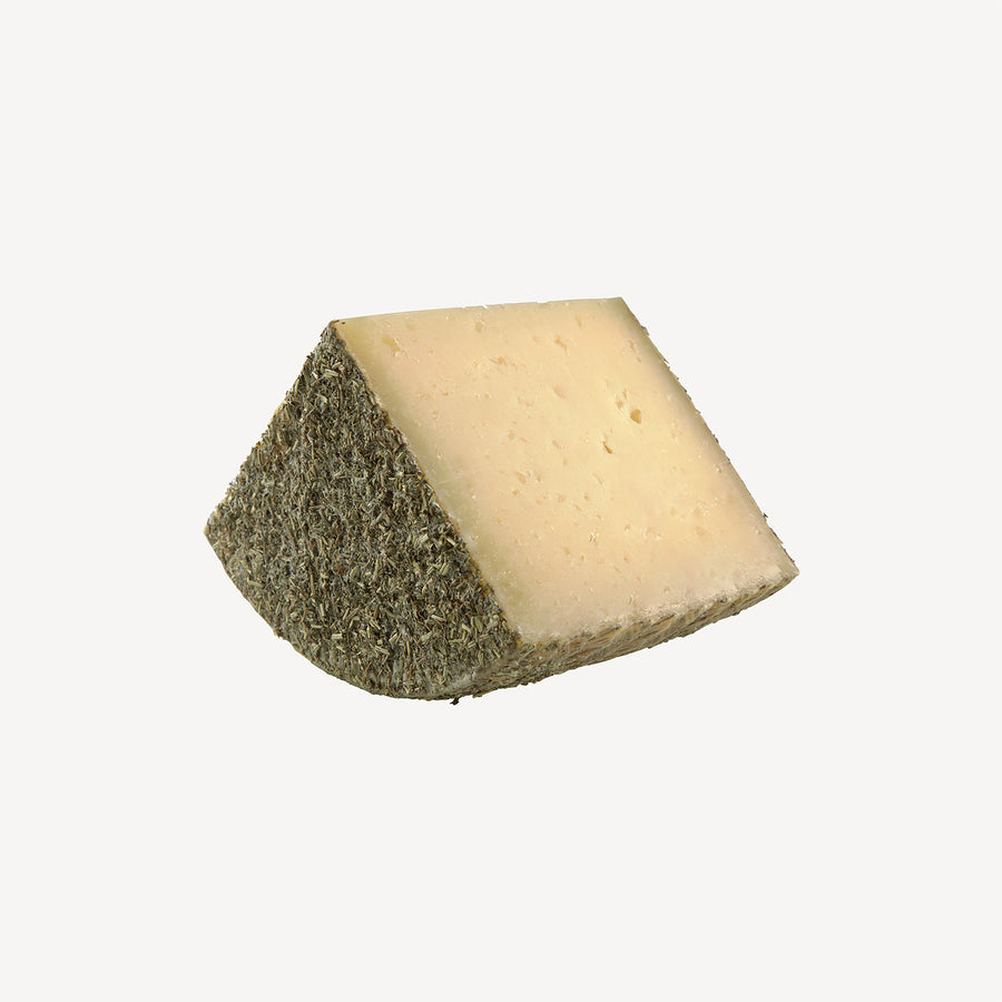 La cuña de queso destaca la riqueza del sabor de oveja y las finas hierbas, una promesa visual de un viaje culinario inolvidable.