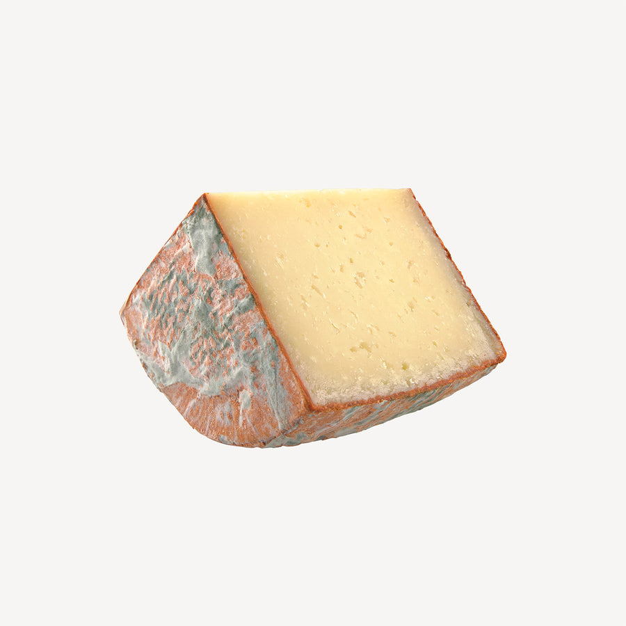 La cuña resalta la mezcla de queso manchego curado y pimentón, un preludio visual a un bocado donde la intensidad y el picante se encuentran.